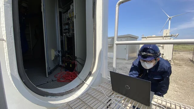 Technician working at a wind turbine tower base